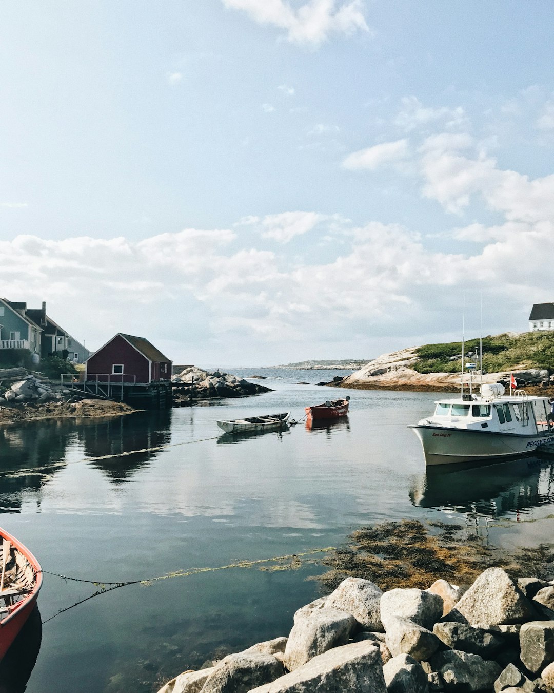 Classic Nova Scotia fishing boat anchored in a serene harbour, showcasing the traditional wooden design and vibrant colours that are a hallmark of the province's rich maritime history.